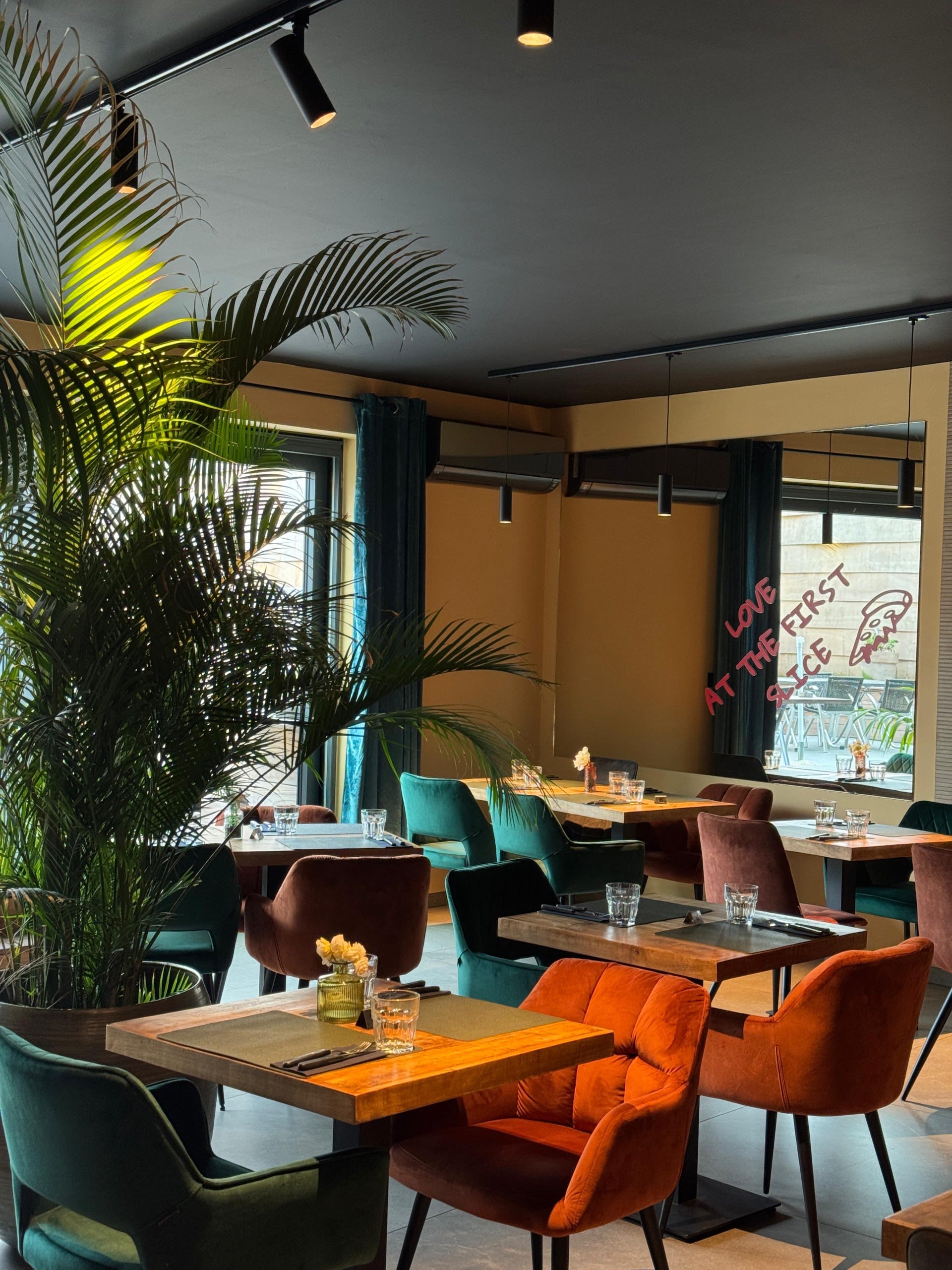 La salle du restaurant Amore, avec ses fauteuils colorés et ses grandes fenêtres